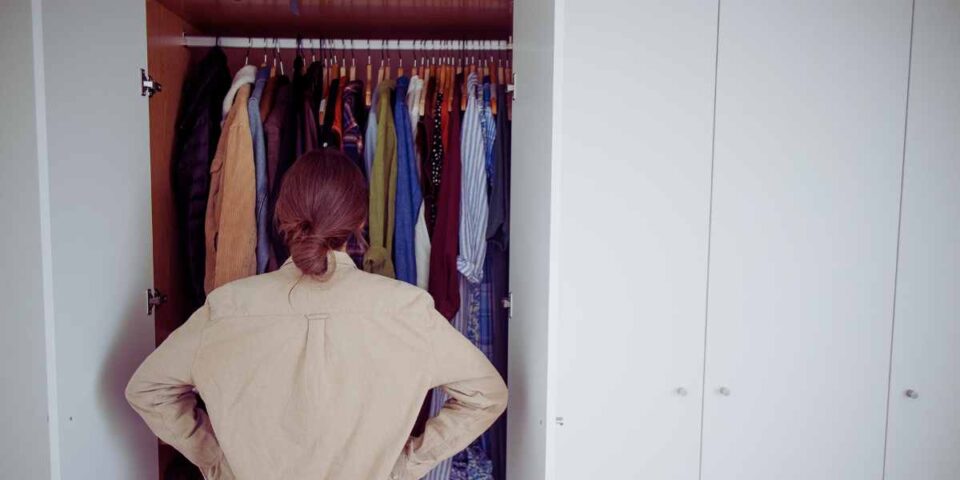 Donna che guardo un armadio pieno ma non sa cosa mettersi